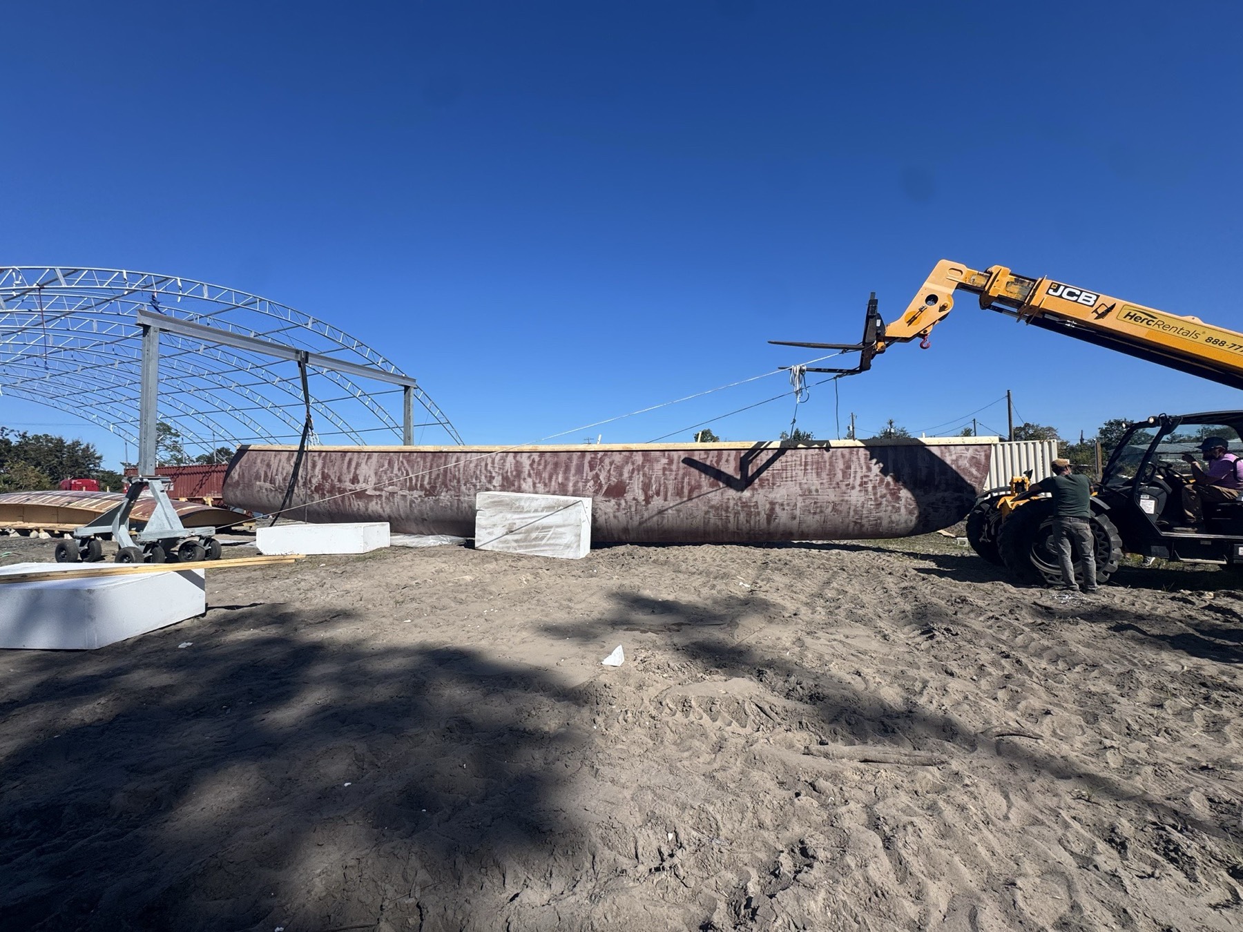 A finished hull panel lifted out of the mold by a telehandler, under a clear sky